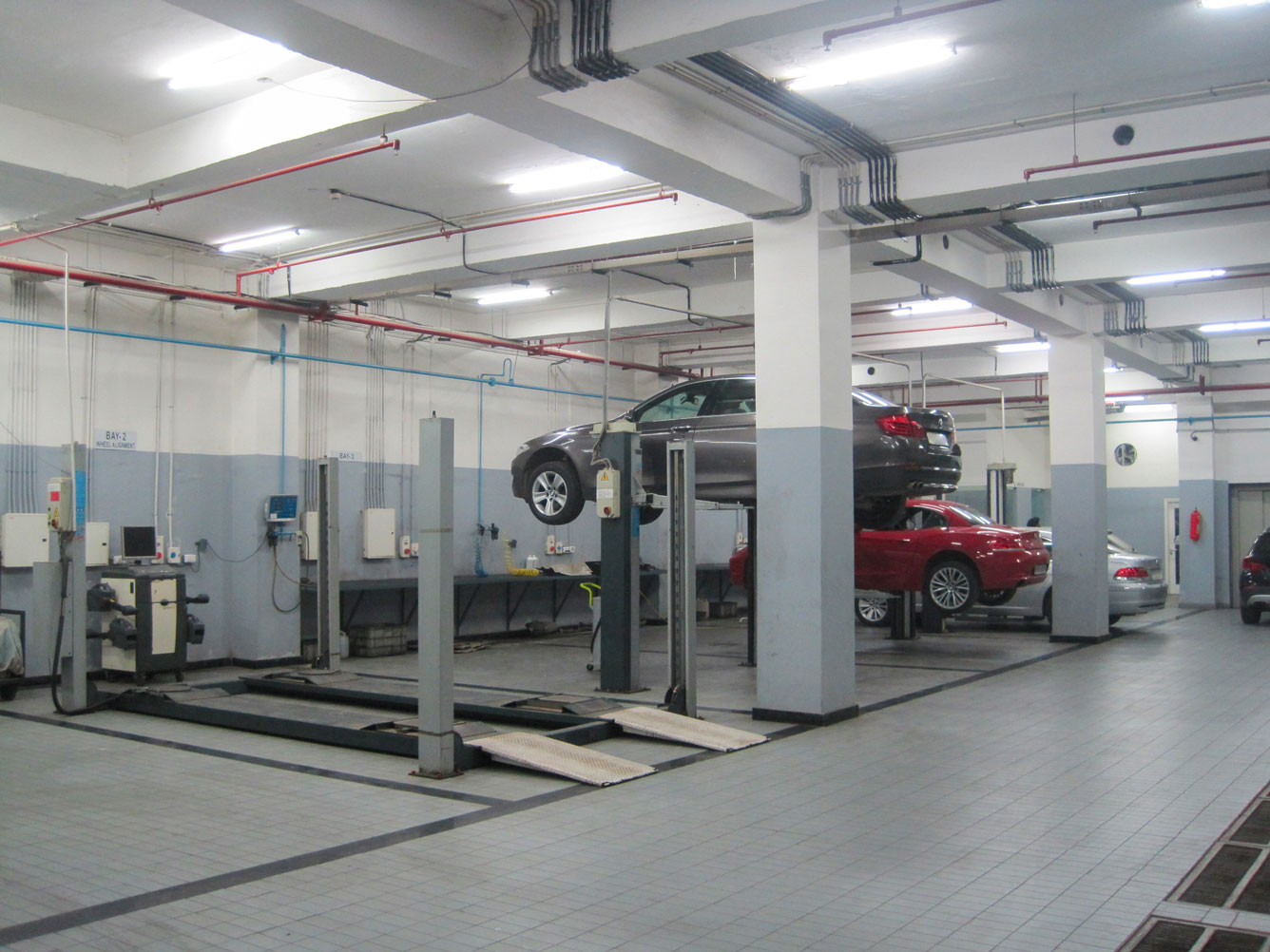 Four-post lift installed in a workshop where three cars are being serviced