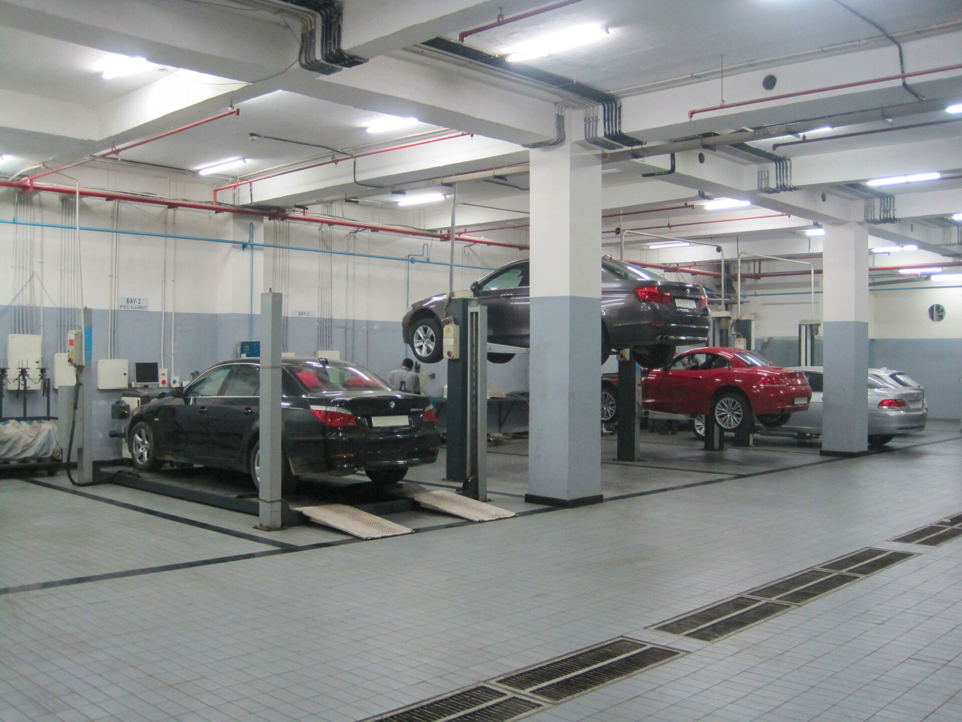 Four cars parked in a dealership are repaired with workshop equipment